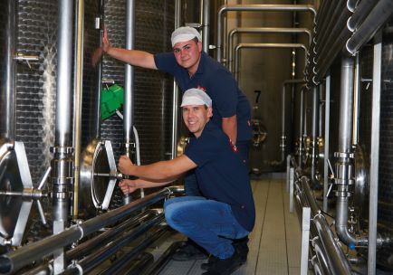 Two young men are standing in the tank farm working on a tank.