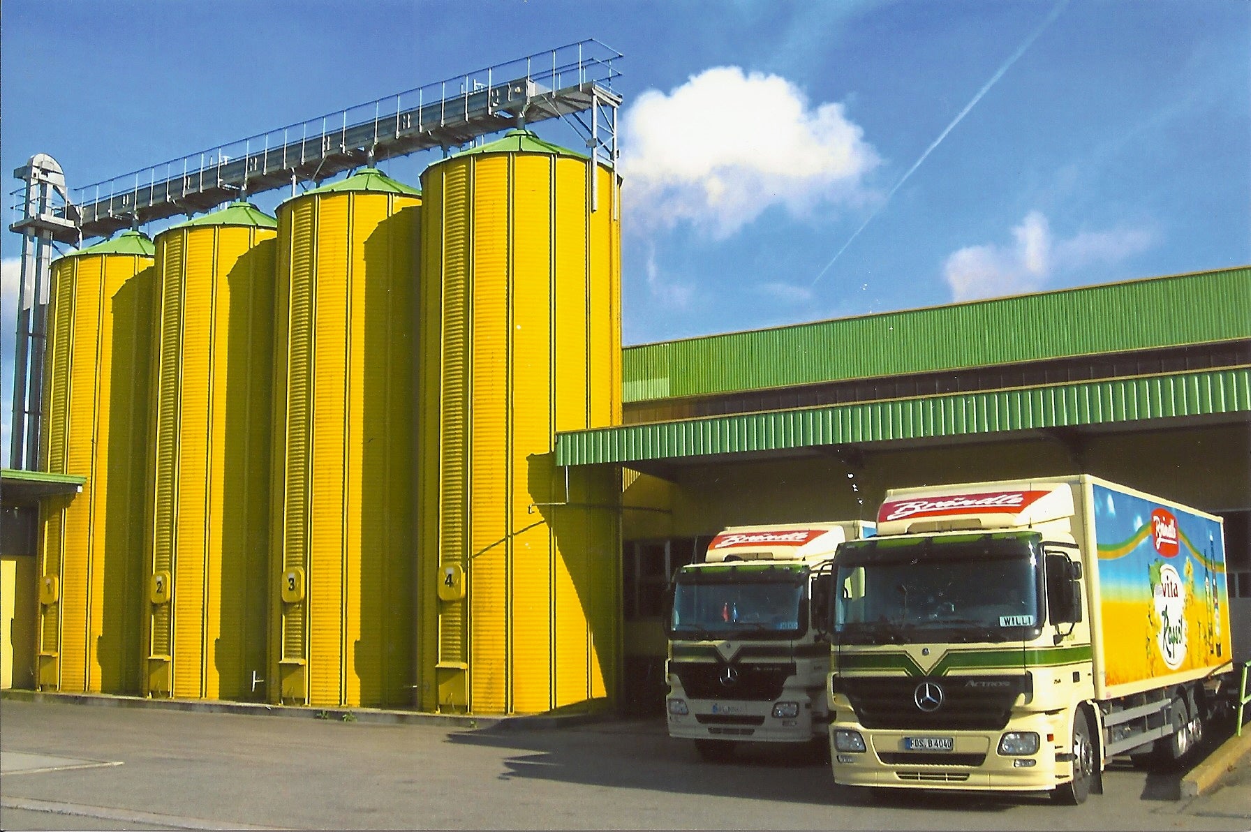 Vor dem Firmengebäude stehen neben vier gelben Silos zwei Brändle-LKW.