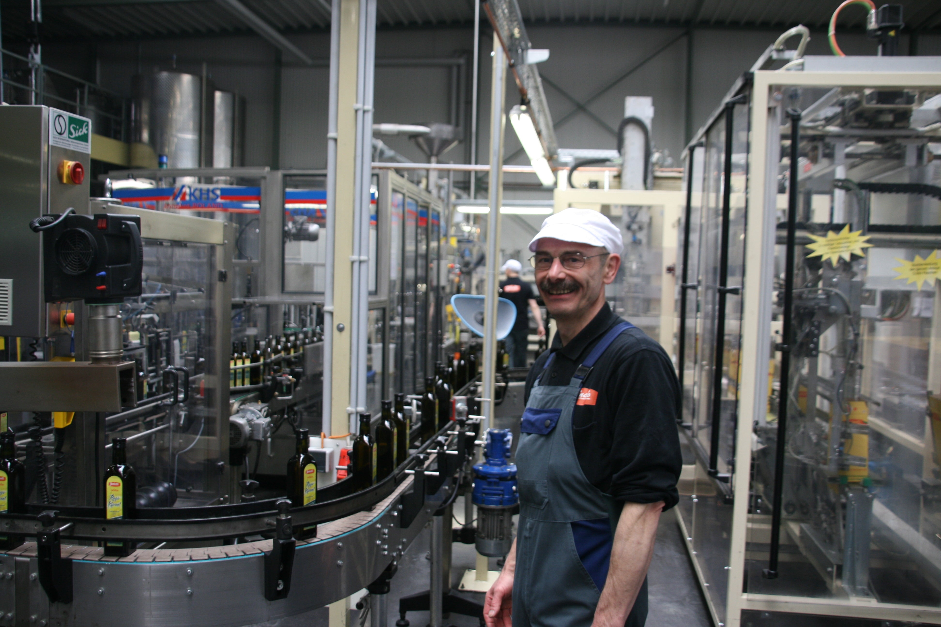 An employee fills rapeseed oil at a filling machine.