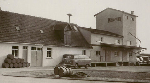 Warehouse and production building with a silo tower. In front of it a yard area with various vehicles